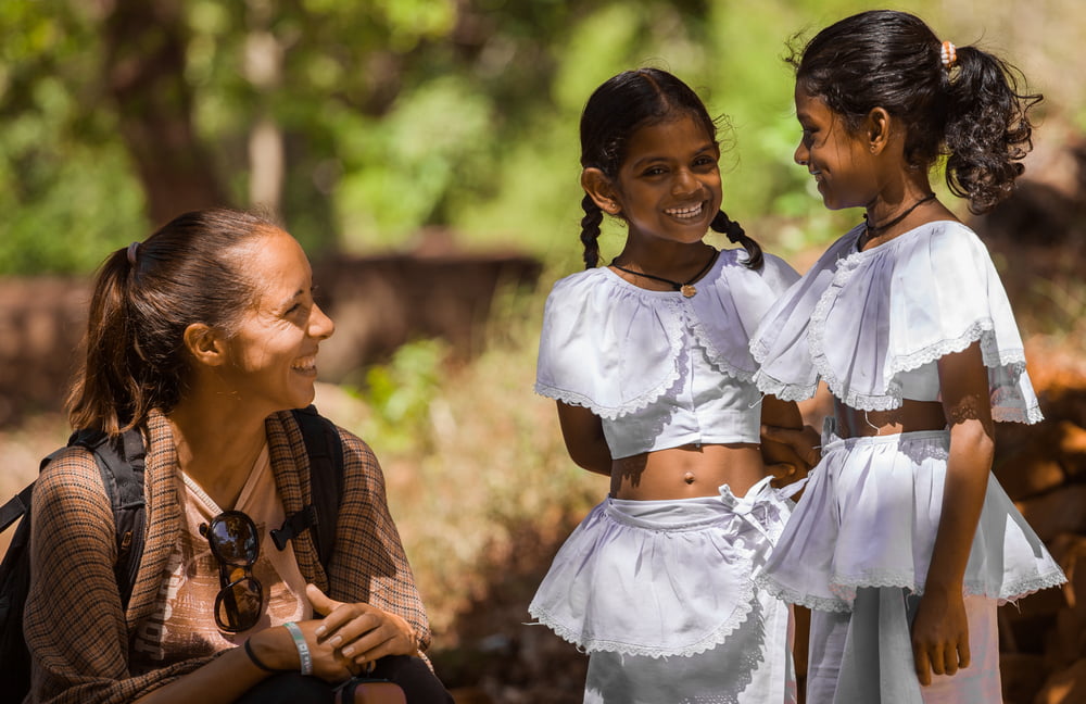 සංචාරකයා දේශීය ගැහැණු ළමයින් දෙදෙනෙකු සමඟ කතාබස් කරයි